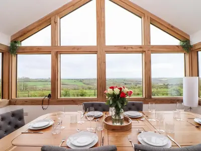 a table with chairs and a vase of flowers on it at Trevilges Cottage in Helston