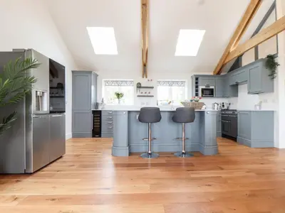 a kitchen with blue cabinets and a wooden floor at Trevilges Cottage in Helston