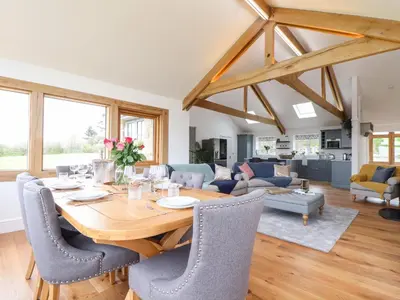 a dining room and living room with a wooden table and chairs at Trevilges Cottage in Helston