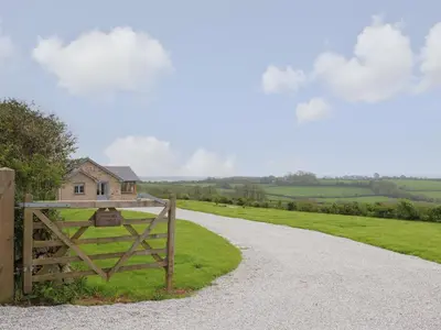 a gate to a house on a dirt road at Trevilges Cottage in Helston