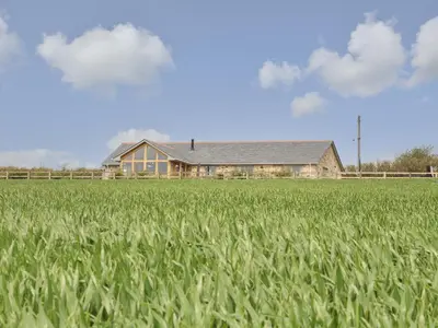 a house in the middle of a field of grass at Trevilges Cottage in Helston