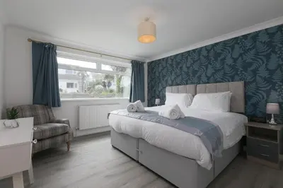 a bedroom with a bed and a chair and a window at Ocean Air in Carbis Bay
