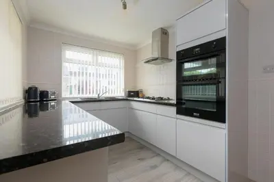 a kitchen with white cabinets and a black appliance at Ocean Air in Carbis Bay