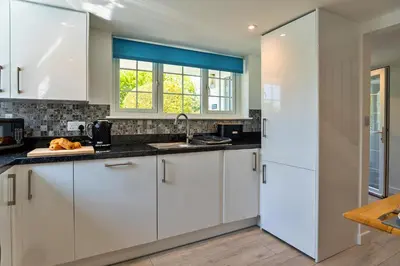 a kitchen with white cabinets and a window at Finest Retreats - Trethew Cottage in Carnbrea