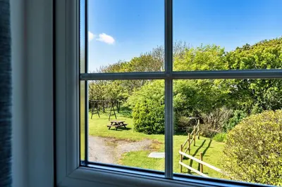 an open window with a view of a park seen through it at Finest Retreats - Trethew Cottage in Carnbrea