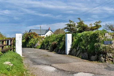 a dirt road with a fence and a house at Finest Retreats - Trethew Cottage in Carnbrea