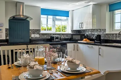 a kitchen with a wooden table with plates and glasses at Finest Retreats - Trethew Cottage in Carnbrea