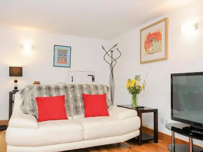 a white couch with red pillows in a living room at Great Brightor Cob Barn in Bodmin