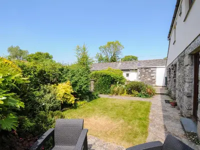 a garden with two chairs and a building at Great Brightor Cob Barn in Bodmin