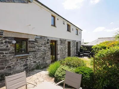 a stone house with two chairs and a patio at Great Brightor Cob Barn in Bodmin