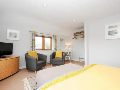 a bedroom with two chairs and a bed and a television at Great Brightor Cob Barn in Bodmin