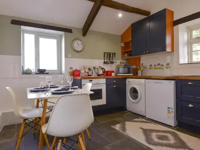 a kitchen with blue cabinets and a table and chairs at Great Brightor Cob Barn in Bodmin