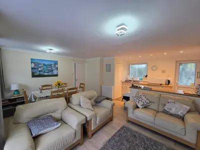 a living room with two couches and a kitchen at 17 River Banks in Liskeard