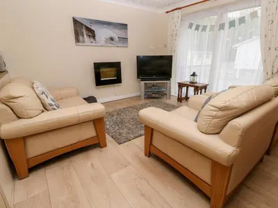 a living room with two chairs and a flat screen tv at 17 River Banks in Liskeard