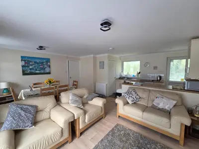a living room with two couches and a kitchen at 17 River Banks in Liskeard