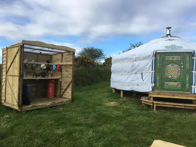 a yurt and a house in the grass at Higher Trenear Farm Yurts in Helston