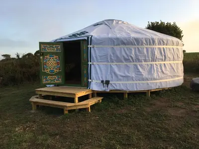 a yurt with a door on a wooden platform at Higher Trenear Farm Yurts in Helston