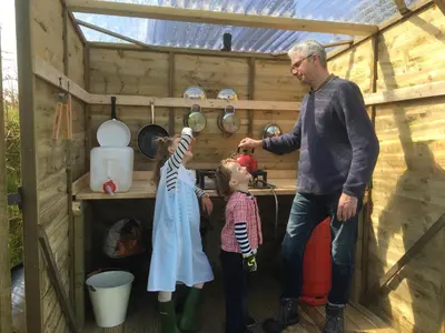 a man and two children playing in a chicken house at Higher Trenear Farm Yurts in Helston