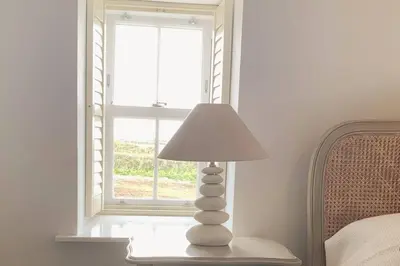 a lamp sitting on a table next to a window at Folly Farm Cottage, Cosy, Secluded near to St Ives in St Ives