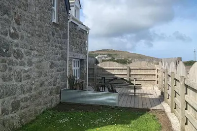 a stone building with a table and a fence at Folly Farm Cottage, Cosy, Secluded near to St Ives in St Ives