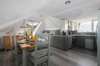 a kitchen with a wooden table and a dining room at Willows in St Ives