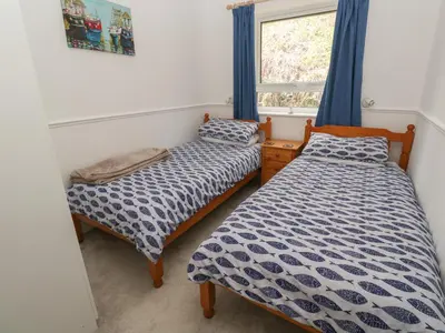 two beds in a room with a window at Badger Sett in Granite Henge near Looe in Looe