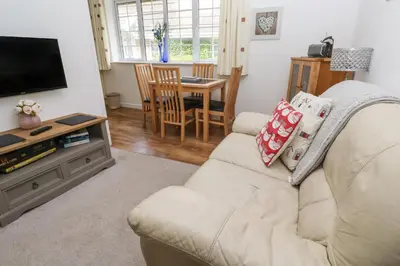 a living room with a white couch and a television at Badger Sett in Granite Henge near Looe in Looe