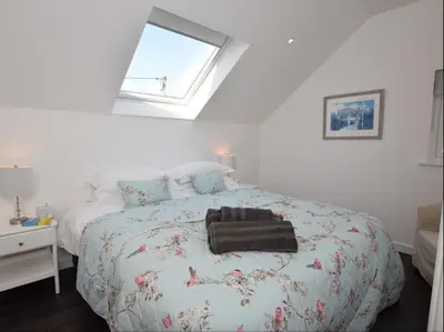 a white bedroom with a bed with a black bag on it at Fernsplatt Farm Lodge in Truro