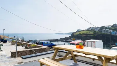 a wooden picnic table sitting on top of a patio at HipNautic, Mevagissey, Sleeps 6 in Mevagissey