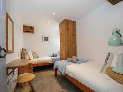 a room with two beds and a wooden cabinet at Mill House in Lostwithiel