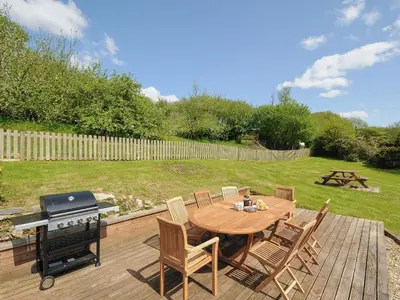 a wooden deck with a table and chairs and a grill at Mill House in Lostwithiel