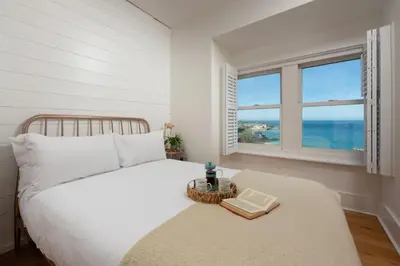 a bedroom with a bed and a window with the ocean at Mordros, St Ives in St Ives