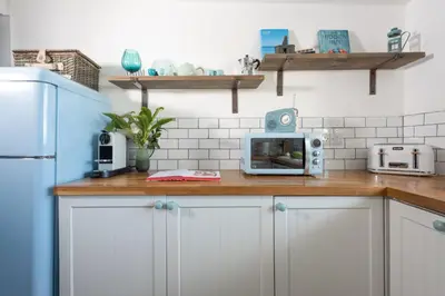 a kitchen with white cabinets and a counter with a microwave at Mordros, St Ives in St Ives