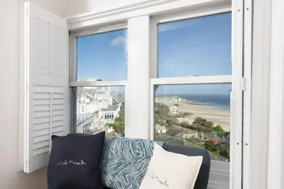 a couch in front of a window with a view of the ocean at Mordros, St Ives in St Ives