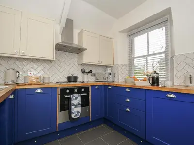 a blue kitchen with white cabinets and an oven at Carvannel Cottages in Camborne