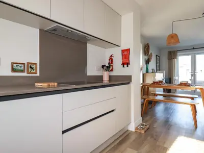 a kitchen with white cabinets and a wooden table at The Waves in Newquay