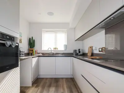 a kitchen with white cabinets and stainless steel appliances at The Waves in Newquay