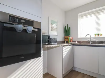 a kitchen with white cabinets and a black appliance at The Waves in Newquay
