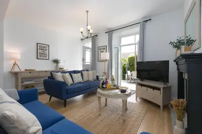 a living room with a blue couch and a tv at Reflections in St Ives