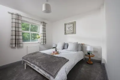 a bedroom with a large white bed with a window at Hoopers Lodge, Hot Tub, Pet Friendly in Ludgvan