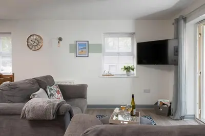 a living room with a couch and a clock on the wall at Hoopers Lodge, Hot Tub, Pet Friendly in Ludgvan