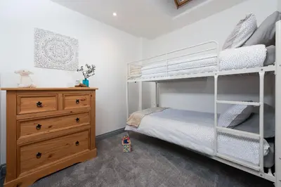 a bedroom with two bunk beds and a dresser at Hoopers Lodge, Hot Tub, Pet Friendly in Ludgvan