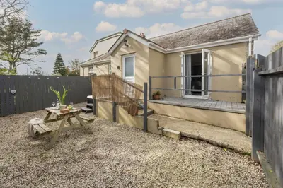 a small house with a fence and a table at Hoopers Lodge, Hot Tub, Pet Friendly in Ludgvan