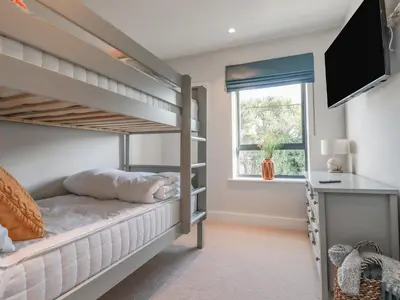 a bedroom with bunk beds with a television and a desk at 7 Longshore in Newquay