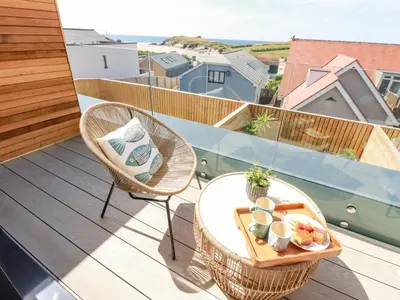 a balcony with two chairs and a table with a tray of food at 11 Ebbtide in Newquay