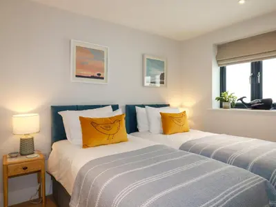 two beds with yellow pillows in a bedroom at 11 Ebbtide in Newquay