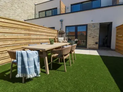 a patio with a table and chairs on grass at 11 Ebbtide in Newquay