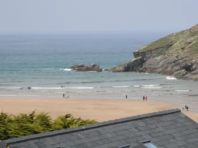 a beach with people walking on the sand and the ocean at 11 Ebbtide in Newquay