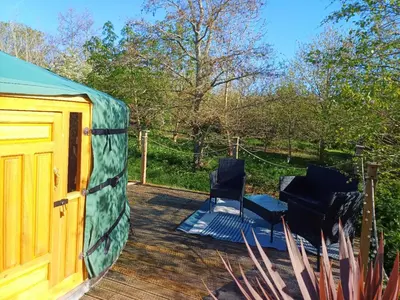 two chairs sitting on a deck next to a tent at The Yurt in Cornish woods a Glamping experience in Penzance