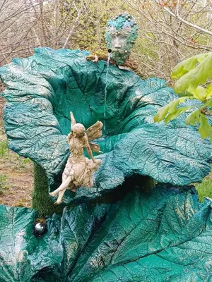 a statue of a woman laying on a large leaf at The Yurt in Cornish woods a Glamping experience in Penzance